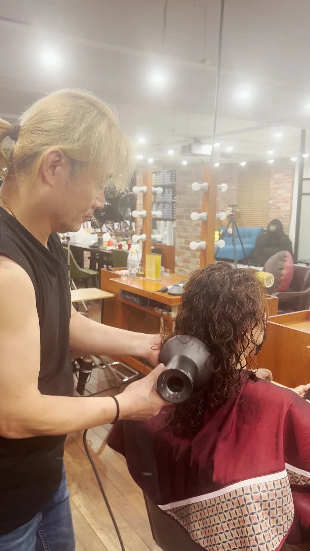 Stylist diffusing a client's curls in a Seoul salon