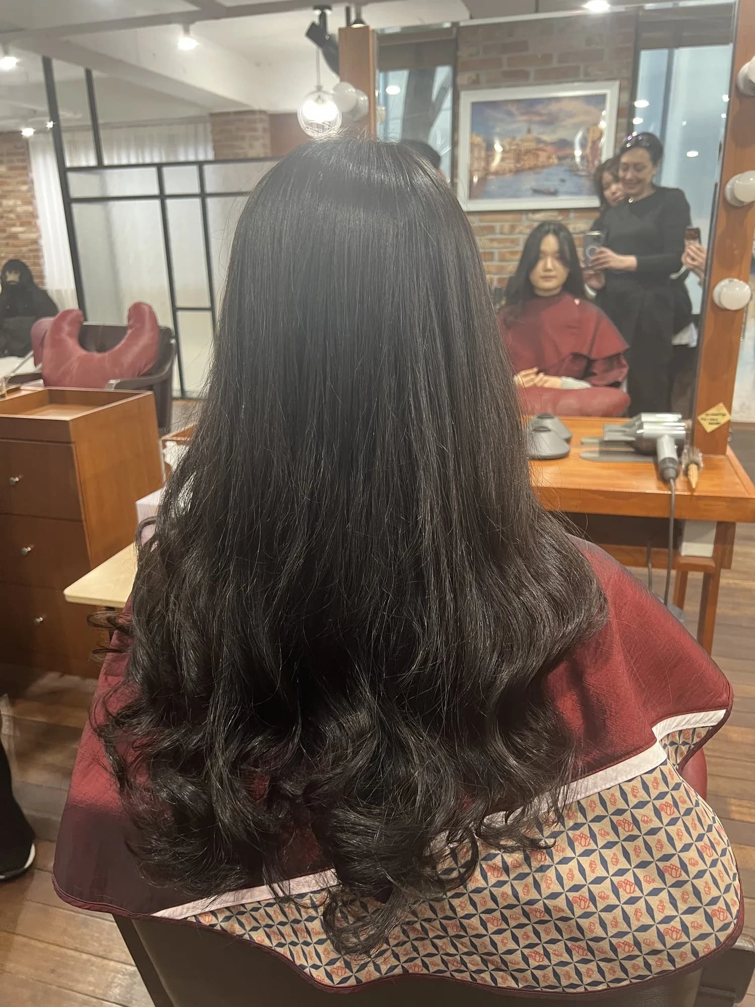 Long dark hair with soft waves from mid-length to the ends after a Korean digital perm, back view, Seoul seminar